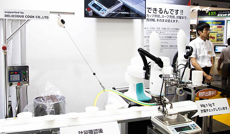 另一角落，川崎重工業展示了「duAro」進行湯品填裝的作業。透過機器手臂完成湯品容器的準備，並且自動進行湯品的填裝與計量的作業。（source：robotstart）